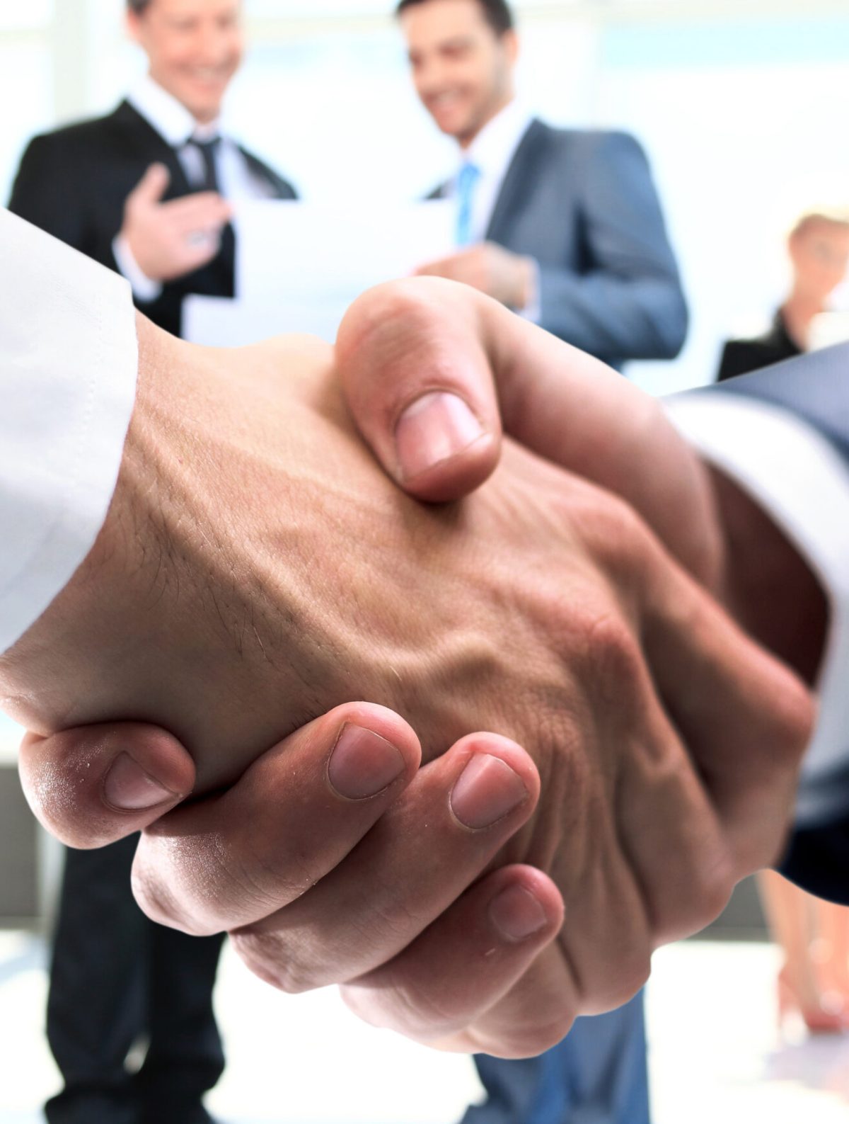 concept of partnership – handshake of business partners closeup of handshake of businessmen on background of employees .in the photo there is an empty space for your text